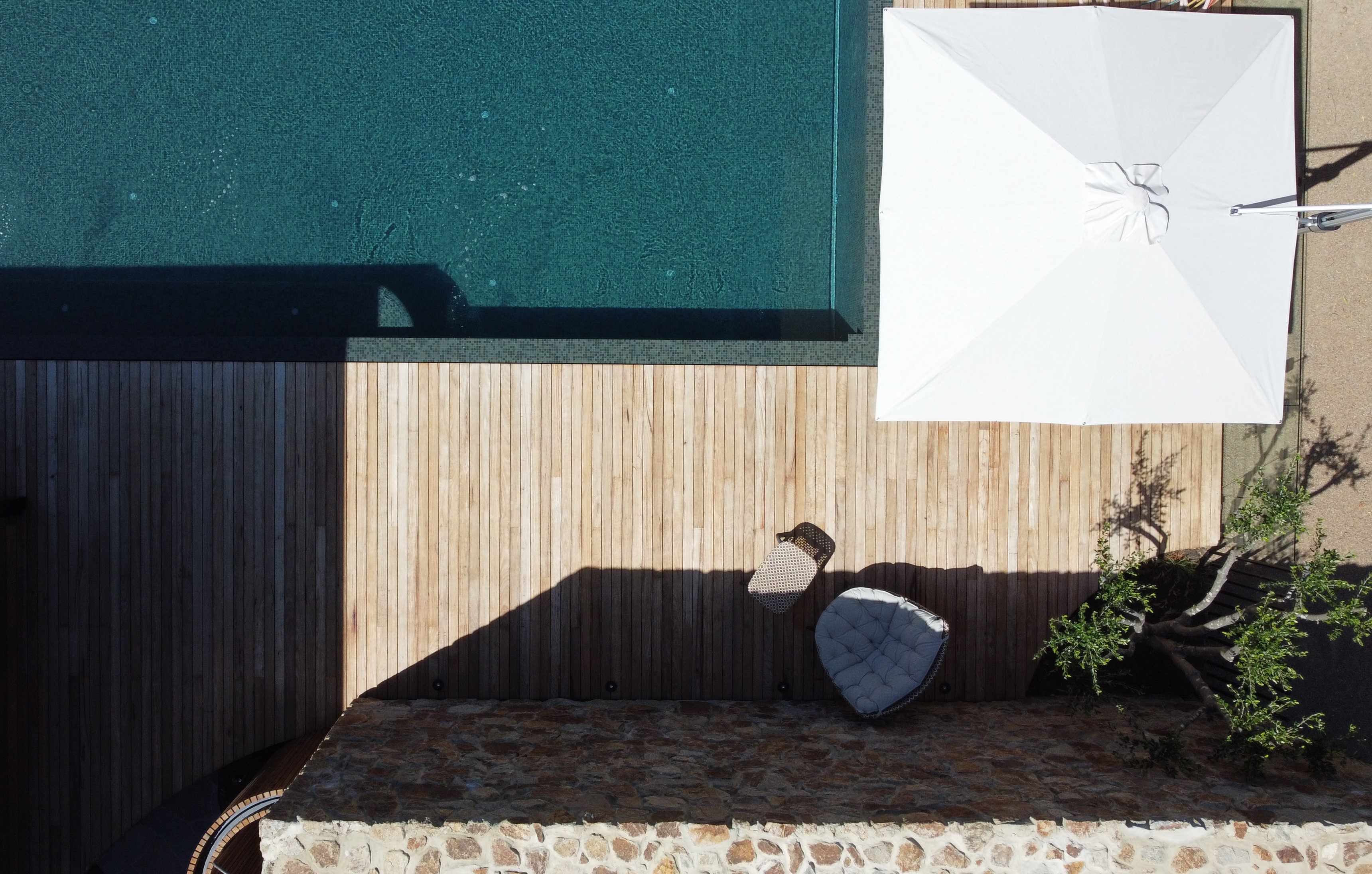 Birds eye view of stonework, deck, pool and large poolside umbrella
