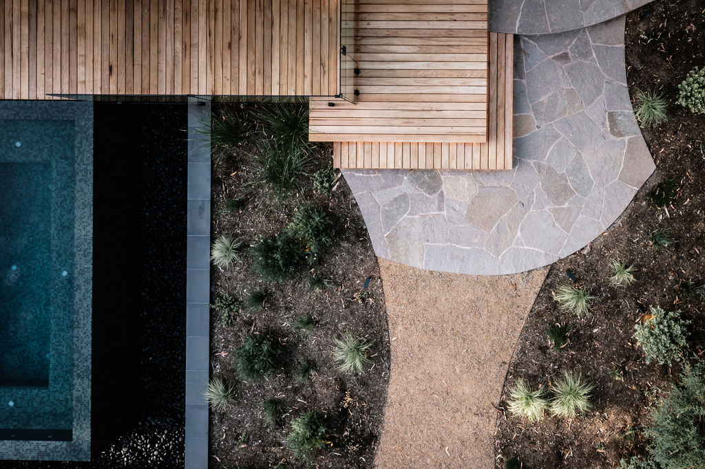 Birdseye view of resort pool, decking, timber landing steps, crazy paving, pathway and landscaping
